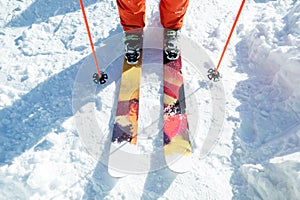 Legs athlete skier in an orange overall on a sport skiing on snow on a sunny day. The concept of winter sports