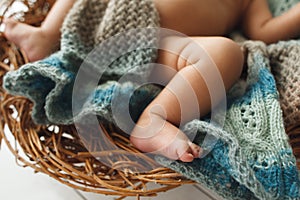 Legs of baby lying on wicker cradle close-up