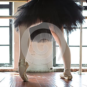 Legs of a ballerina closeup. The legs of a ballerina in old pointe. Rehearsal ballerina in the hall. Contour light from the window