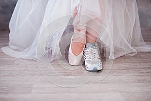 Legs of a ballerina, one foot shod in sneakers other in pointe shoes