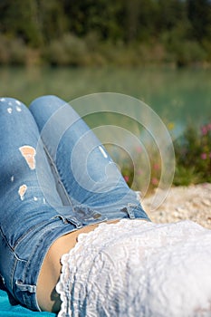 Legs with blue jeans of a girl which is spending her free time on the pebble beach