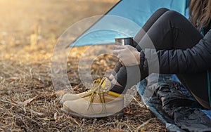 Legs in boots of woman camping in forest