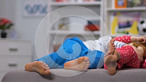 Legs of boy and girl lying on sofa, resting after active leisure, daytime sleep