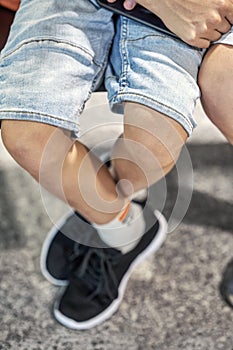 Legs of boy sitting in waiting room of airport near brother