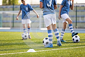 Legs of Boys Soccer Players on Grass Training Venue. Kids in Light Blue Shirts Kicking Soccer Balls