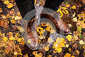 Legs in brown leather boots on wet asfalt photo