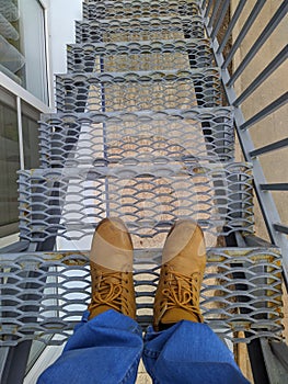 legs build on the steps of a metal staircase first person view