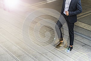 Legs of businessman wear black suit walking stepping up stair in modern city, business grow up and success concept