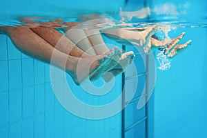 legs of caucasian family friends underwater in swimming pool.