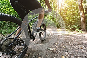 Legs of caucasian man riding bike in the forest