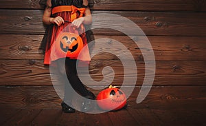 Legs of child girl in witch costume for Halloween with pumpkin