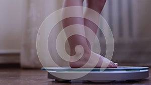 The legs of the child on the scales. A little girl gets bare feet on the scales. The concept of weight loss and excess