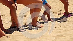 Legs of children playing tug of war on the sand
