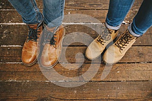 Legs of couple in boots on the wooden floor outdoors