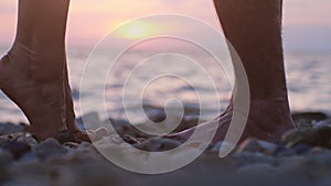 Legs of couple in love during the date near the sea on the beach during beautiful sunset.