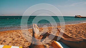 Legs of Couple People Lying on Beach Sun Lounger near the Red Sea