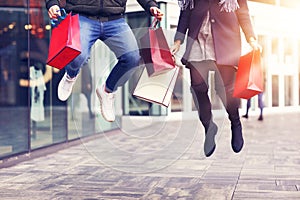 Legs of couple with shopping bags after shopping in city