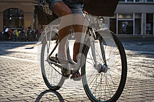 Legs of a cyclist pedaling on a stone bridge of the old city in the light of the evening sun