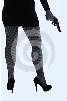 Legs of dangerous woman with handgun and black shoes silhouette