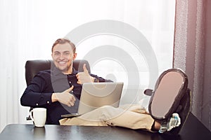 Legs on desk, laptop and smiling man thumbs up symbol