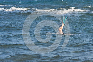 Legs of diving man in the swim flippers above the storm waves