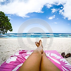 Legs with fake spray tan on sun lounger on tropical beach with p photo