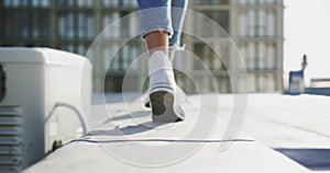 Legs of fashionable young woman walking on urban rooftop