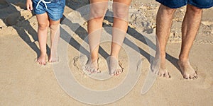 Legs and feet of family standing on sand sea beach on summer holiday
