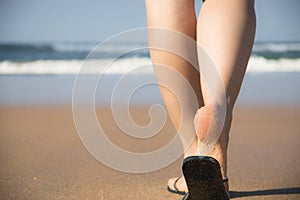Legs and feet of a girl walking towards the sea