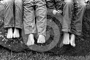 Legs and feet of siblings sitting on rock