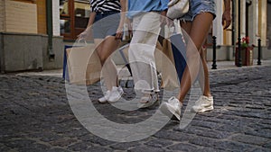 Legs of female friends walking with shopping bags