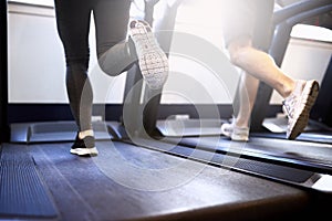 Legs of Fit Couple Exercising on Treadmill Device