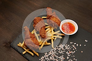 Legs and fries with sauce close-up on a slate plate