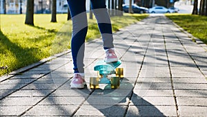Legs of girl in jeans riding skateboard, back view.