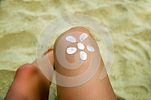 Legs of a girl lying on a beach deckchair by the sea. The sun, painted on sunburnt skin of the foot with sunscreen