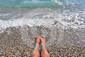 Legs of a girl on a pebbly beach