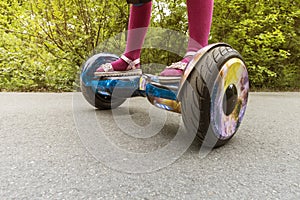 Legs of girl riding on self-balancing mini hoverboard in city Park. Electronic scooter outdoors - personal portable eco transport photo