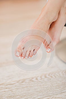 Legs of a girl sitting on a chair in a room with a French pedicure. Close-up