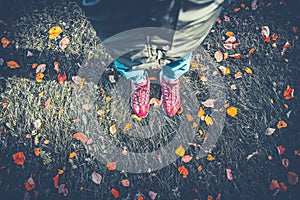 Legs of a girl in sneakers grass, strewn with autumn leaves, top view