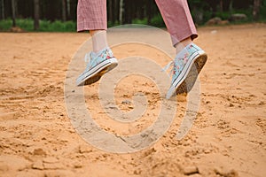 legs of a girl in sneakers run along a sandy beach. Sports recreation on the coast