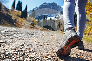 Legs of a girl in sneakers. Walking on the road in the mountains