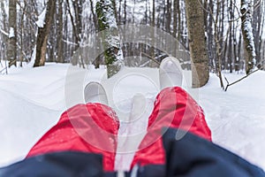 Legs of girl in sweatpants laying down on snow. Winter holidays, weekend, vacation concept
