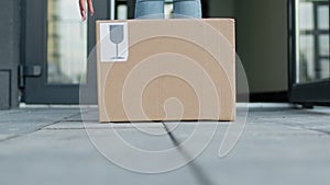 Legs Of Girl Who Comes To The Door And Opens It. She Lifts Box From The Ground.