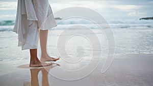 Legs going summer beach on cloudy day closeup. Relaxed woman leaving footprints