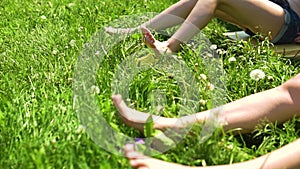 Legs in the grass women`s white on a green background move, and sunbathe, happy girls