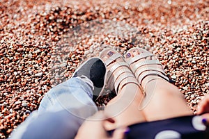 The legs of a guy and a girl in sandals in beach sand