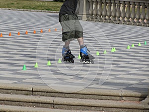 Legs of guy on rollerblades. Rollerblader and slalom cones