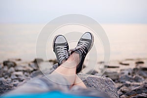 The legs of a guy in sneakers on the beach