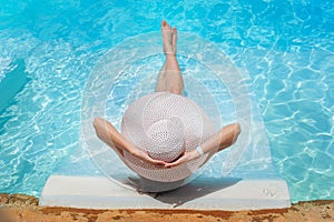 Legs and a hat of woman in the pool water