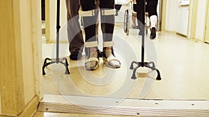 Legs of invalid in orthosis walking with support of two walking cane